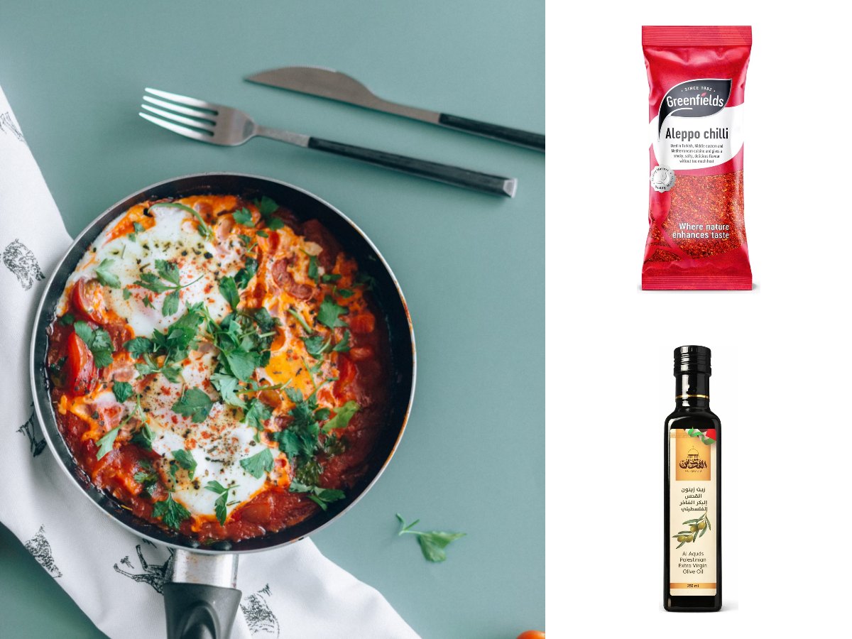 Shakshuka in a frying pan, eggs poached in a red pepper and tomato sauce with parsley, with Greenfields Aleppo chilli flakes and Al-Quds Palestinian olive oil