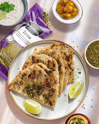 Za'atar flatbreads (manakish) on a plate beside a Greenfields za'atar pack