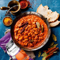 Chicken tikka masala in a pan with naan beside a Greenfields tikka masala pack