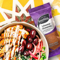 Shawarma bowl with garlic sauce and olives beside a Greenfields Lebanese shawarma pack