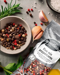Bowl of mixed peppercorns beside a Greenfields five mix peppercorns pack