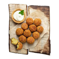 Freshly fried falafel balls on a wooden board with a yoghurt dip
