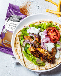 Chicken shawarma flatbread with salad and garlic sauce beside a Greenfields pack