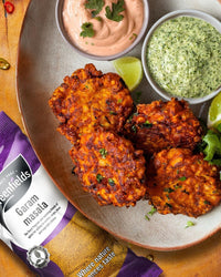 Onion bhajis with dips beside a Greenfields garam masala pack