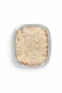 Madina date paste topped with sesame seeds in a clear tray