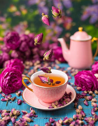 Cup of rose bud tea with a pink teapot and roses