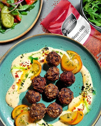 Meatballs on a yoghurt sauce sprinkled with Aleppo chilli, beside a Greenfields pack
