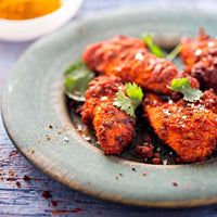 Tandoori chicken pieces on a plate with fresh coriander