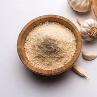 Wooden bowl of garlic powder with garlic cloves